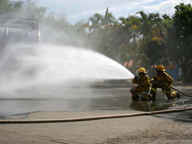 Firefighters during live fire training using a hose to put out a fire