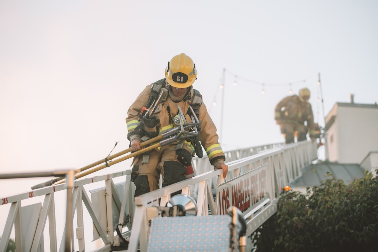 firefighter going down a ladder with equipment in hand